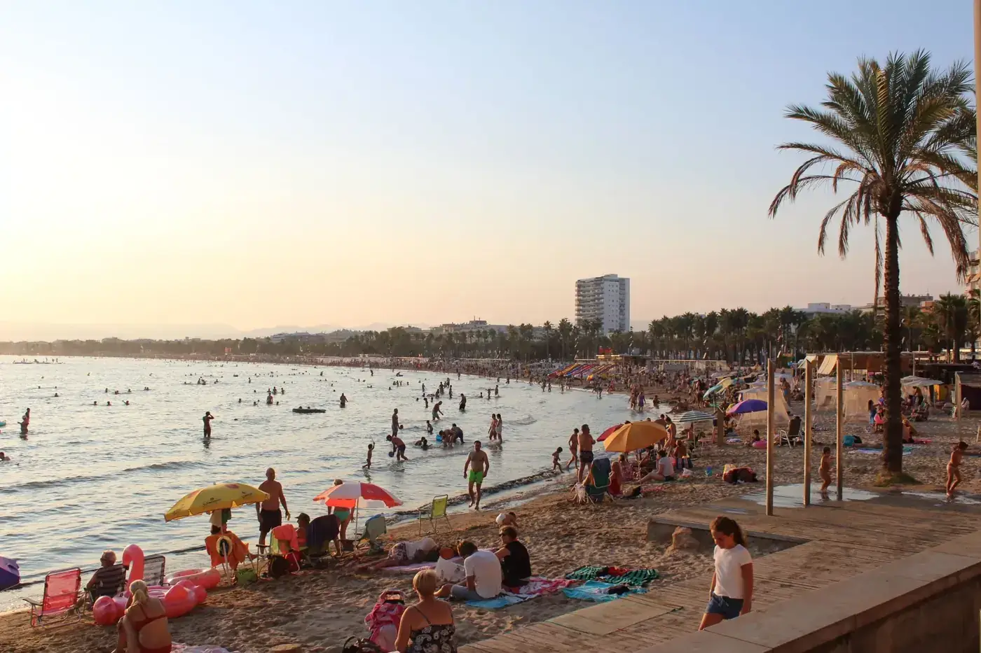 Crowded beach in Spain with people enjoying a sunny day at the shore.