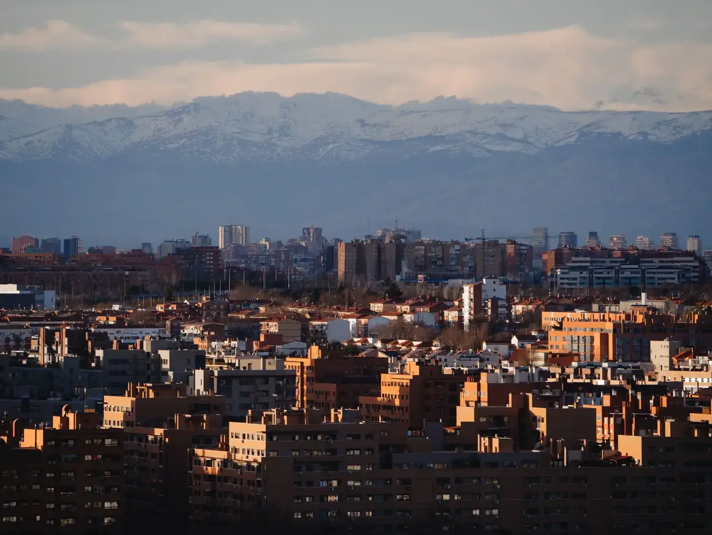 A stunning view of Madrid's urban landscape with the snow-capped Sierra de Guadarrama in the background.