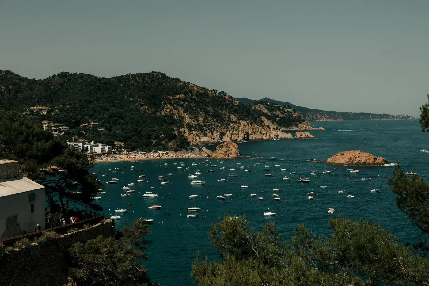 Breathtaking view of boats along Tossa de Mar's rugged coastline in Cataluña, Spain.