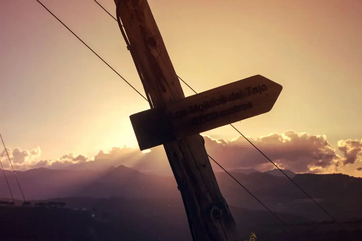 Scenic sunset view with a wooden signpost in Ronda, Spain, guiding to Los Molinos del Tajo.