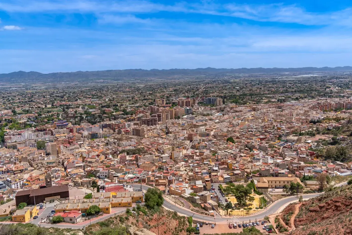Aerial view of Lorca, Murcia, Spain showcasing the city's architecture and landscape under a clear blue sky.