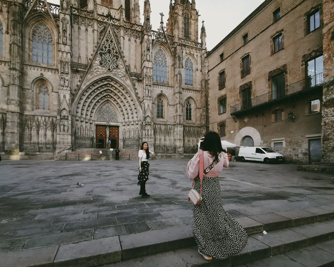 Two women capture the Gothic facade of Barcelona Cathedral, a landmark of Christian heritage in Spain.