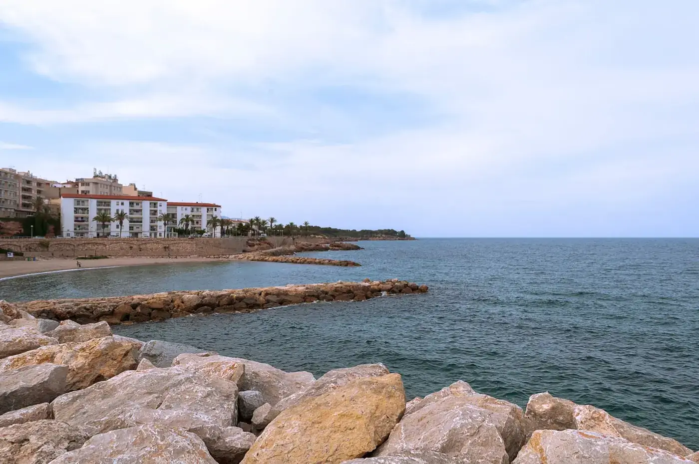 Breathtaking rocky coastline of L'Ametlla de Mar, Spain, with serene blue waters and coastal buildings.