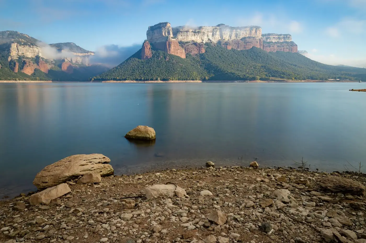 Tranquil scene of Sau Reservoir with majestic mountains under clear skies.