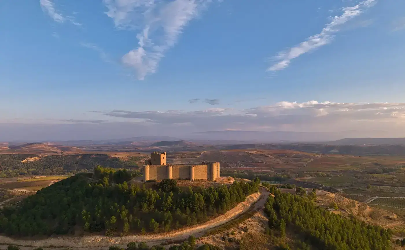Stunning aerial view of Clavijo Castle surrounded by scenic La Rioja landscape at sunset.