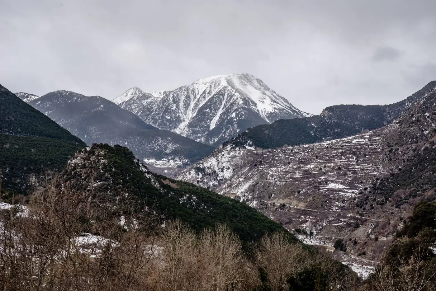 Scenic view of the snowcapped Pyrenees under overcast skies in Espot, Spain, showcasing natural beauty and rugged terrai