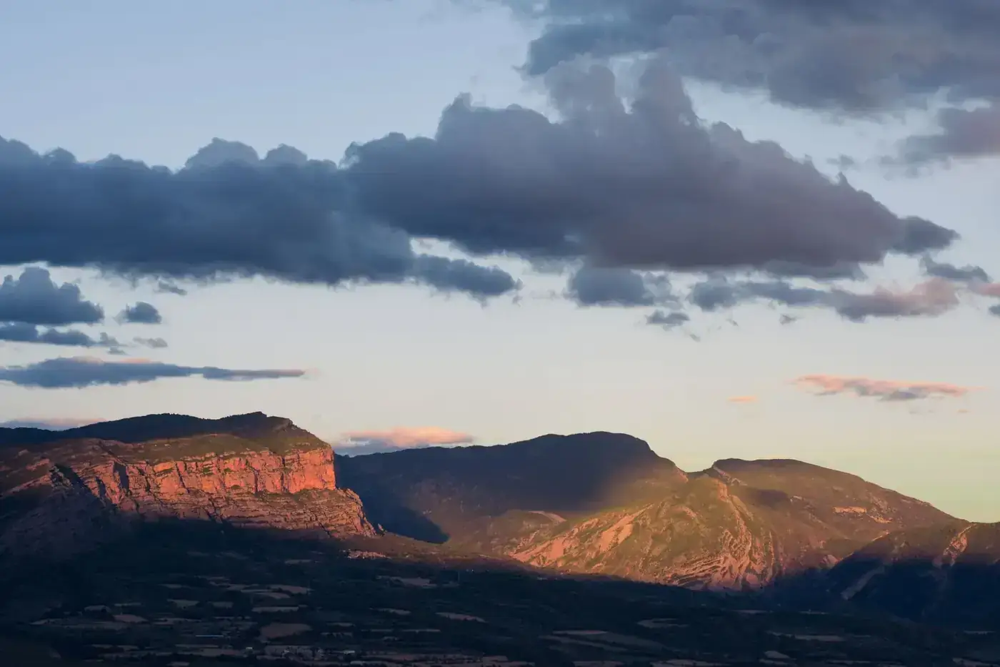 Dramatic clouds over Torallola mountains at sunset, capturing nature's beauty in Spain.