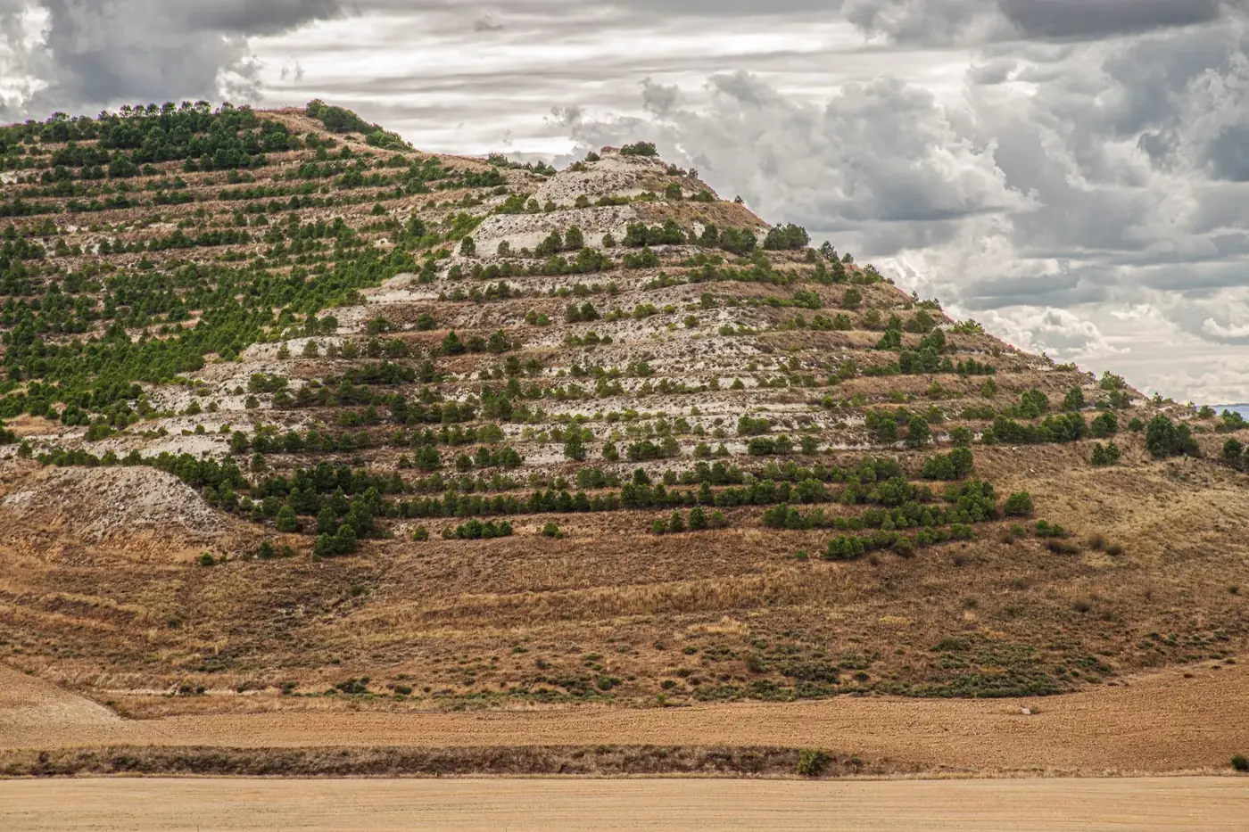 A breathtaking view of terraced hills under a dramatic cloudy sky in Soto de Cerrato, Spain.