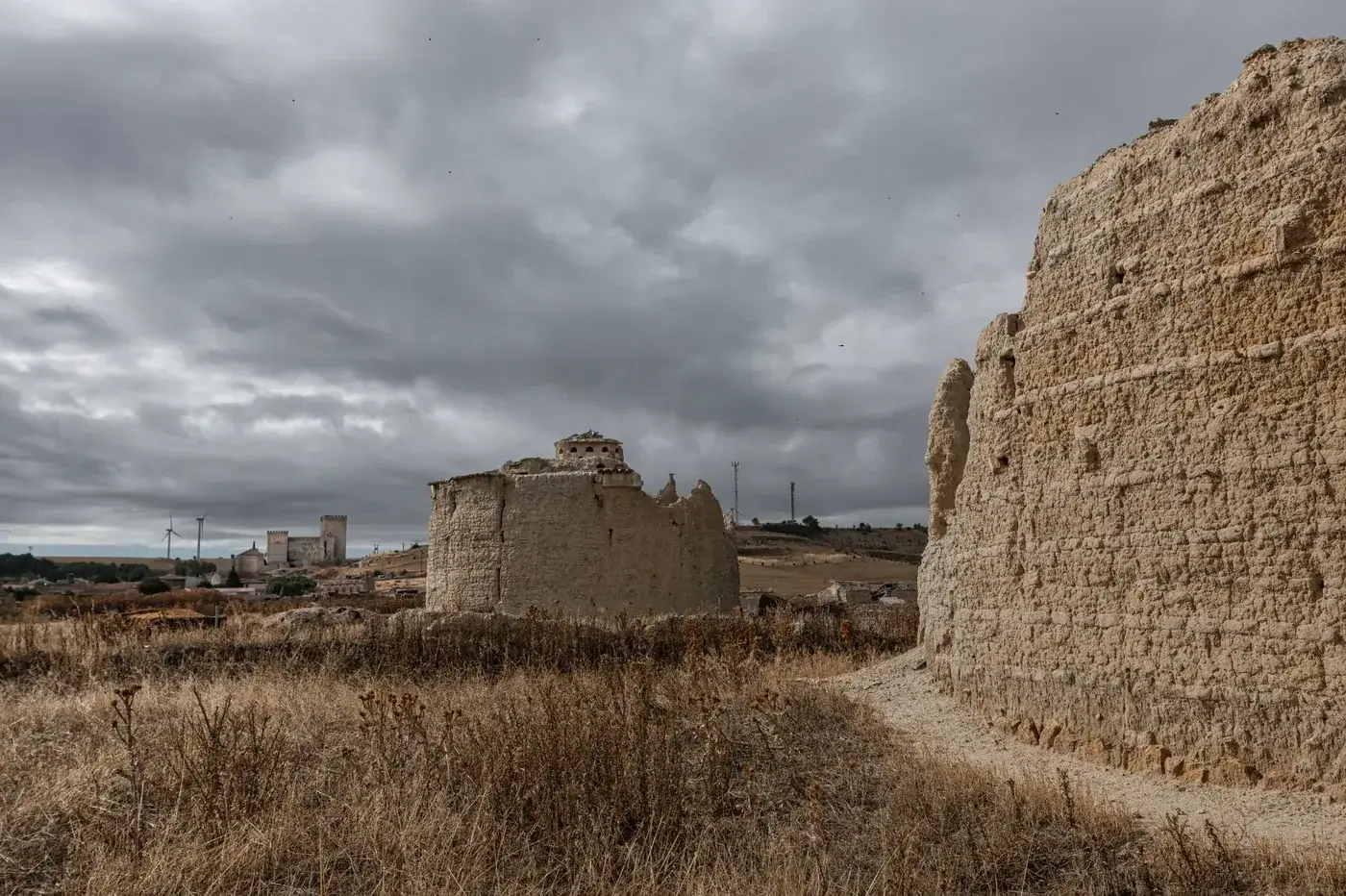 Ancient stone ruins in Ampudia, Spain, with dramatic cloudy skies and rustic landscape.