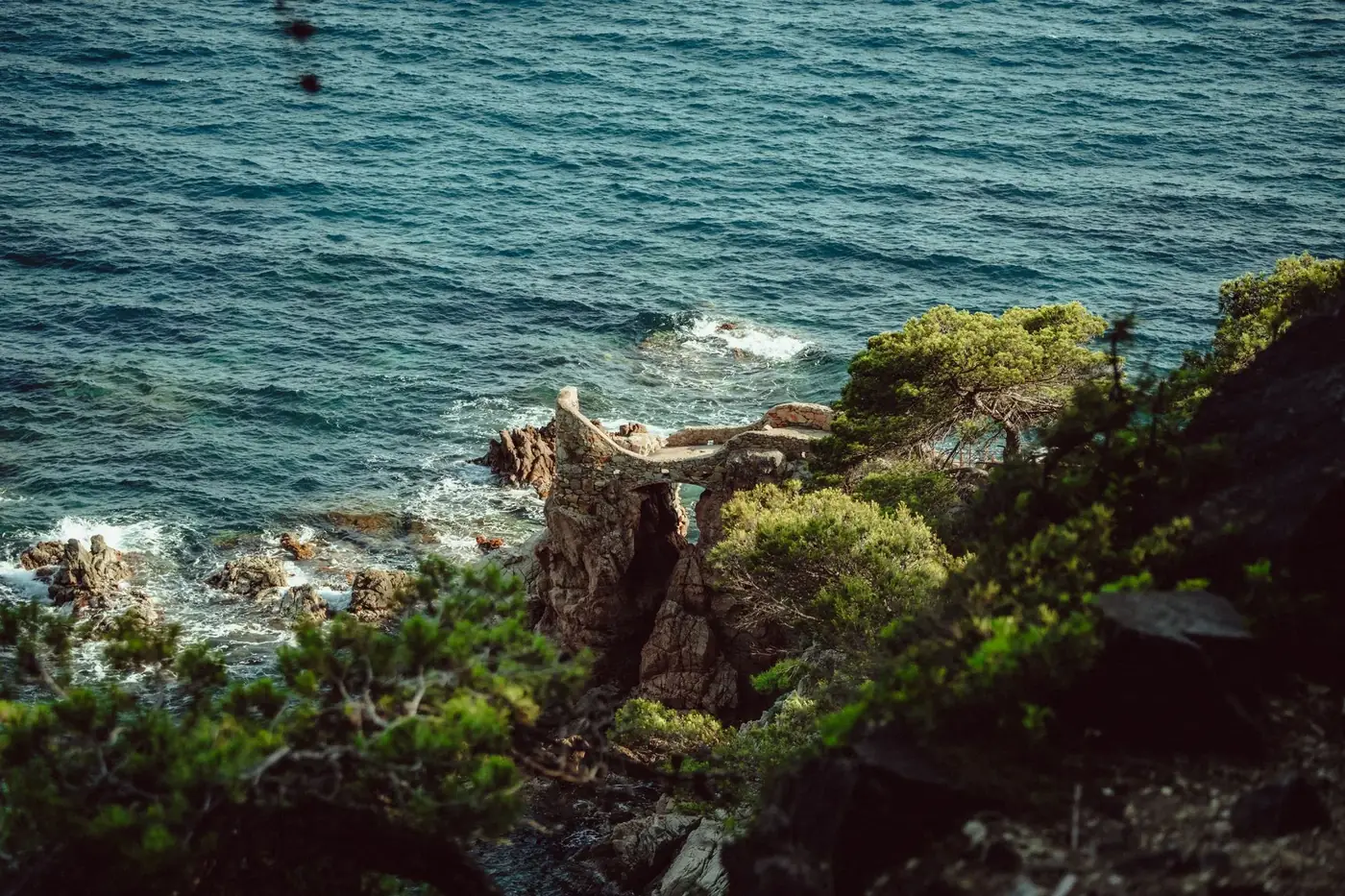A stunning coastal view of cliffs and blue ocean in Lloret de Mar, Spain during the day.