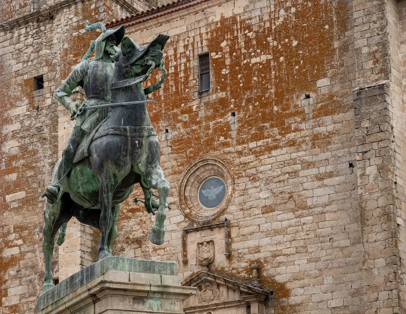 Equestrian statue of Francisco Pizarro in Cáceres, showcasing Gothic architecture.