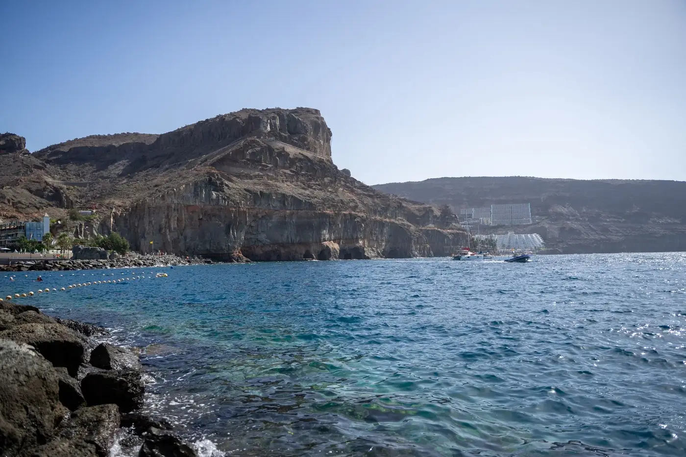 Breathtaking view of Mogán's rocky coastline under a clear blue sky, ideal for travel enthusiasts.