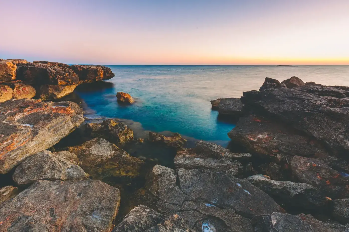 A tranquil sunset view over the rocky Mediterranean coast in Illes Balears, Spain.