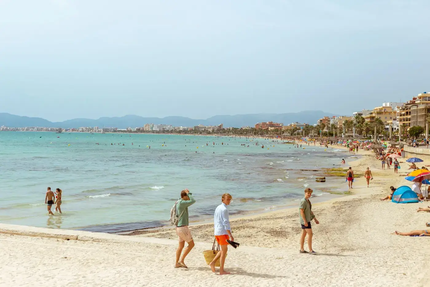 Idyllic summer day at a lively beach in Mallorca with people enjoying the sun and sea.