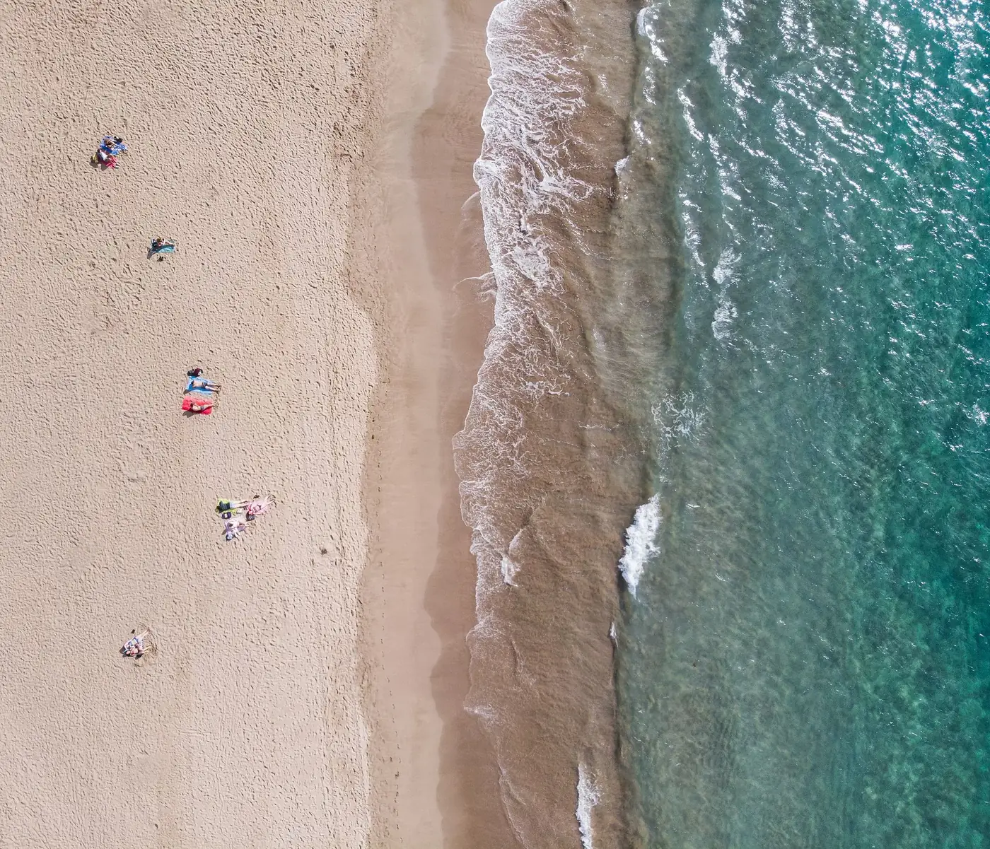 Drone shot of Las Palmas beach showing sandy shore and turquoise ocean waves.