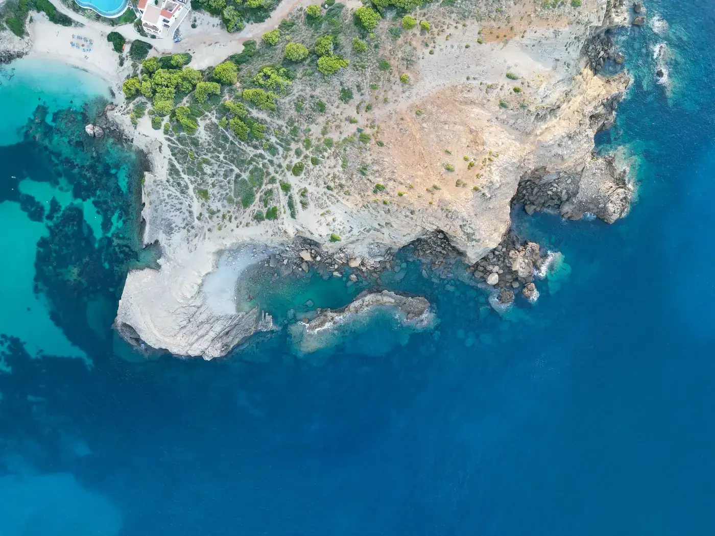 Stunning aerial view of Arenal d'en Castell's rocky coastline and turquoise waters in Menorca, Spain.