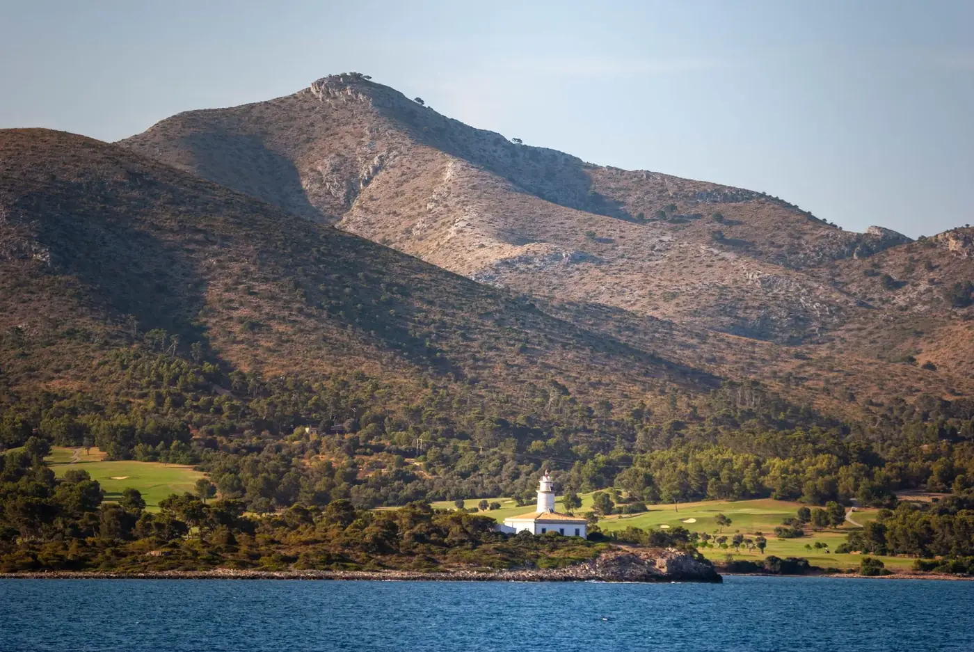 Picturesque lighthouse nestled in the coastal mountains of Islas Baleares, Spain.