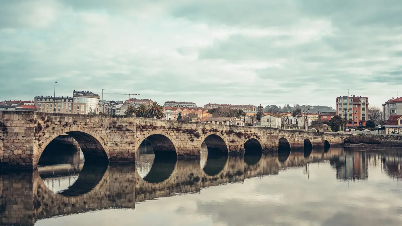 Scenic view of a historic stone bridge with reflections in Burgo, Spain.