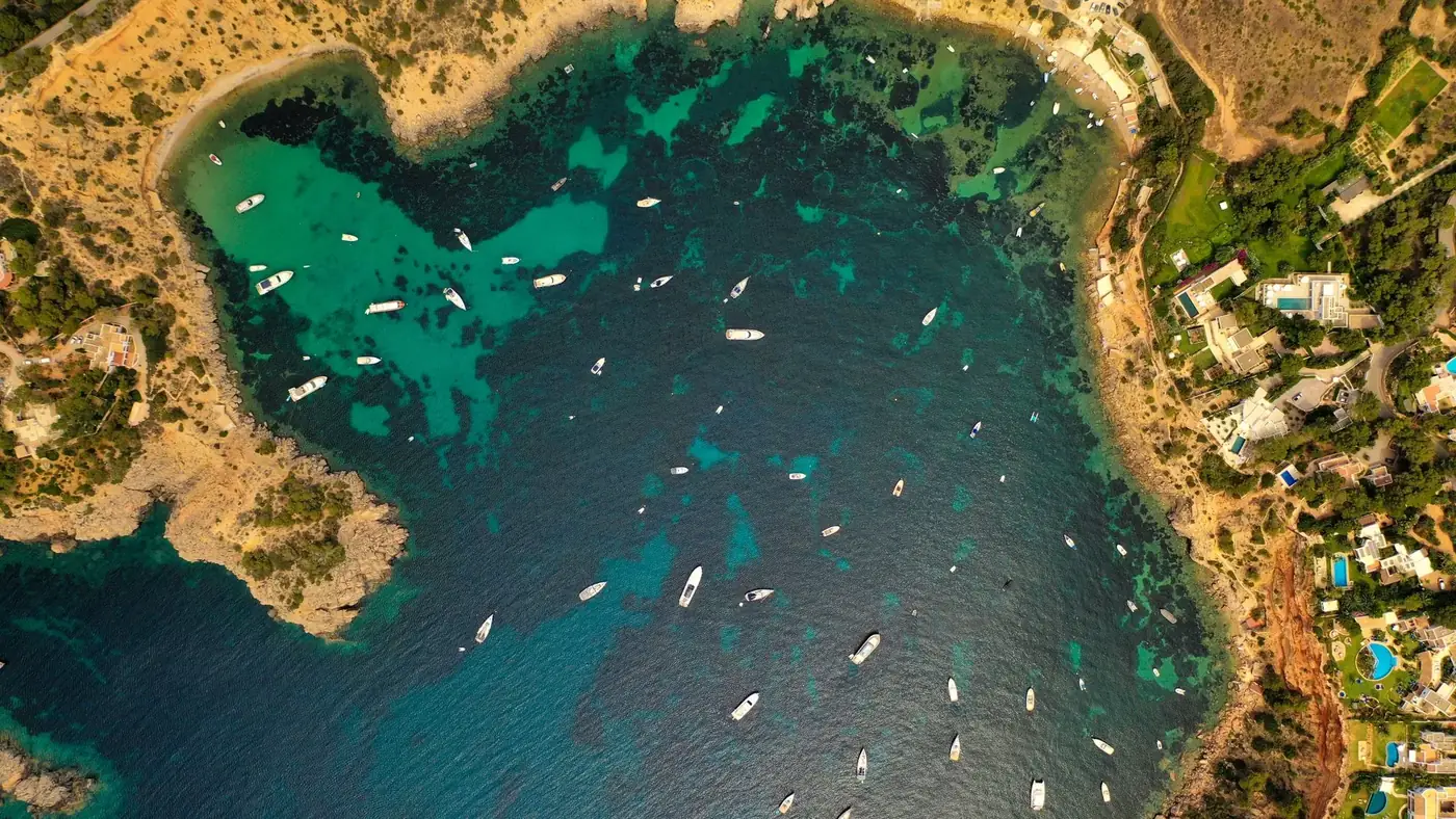 Stunning aerial view of Ibiza's coastline with boats and clear waters.