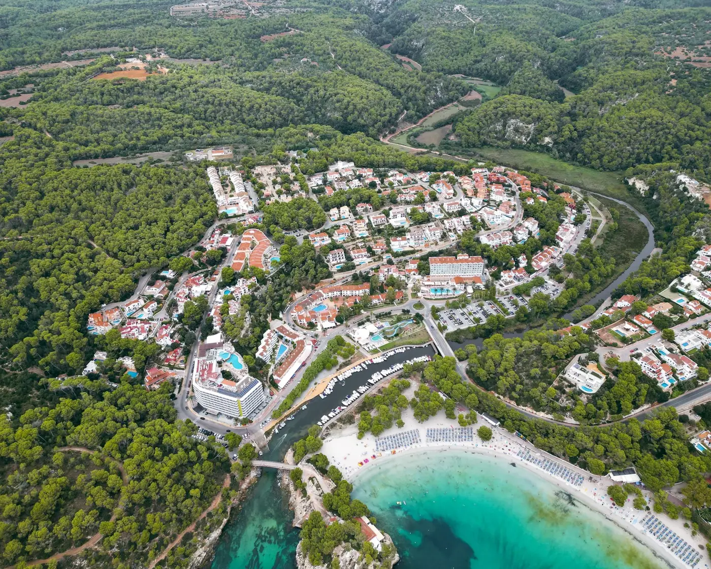 Stunning aerial view of Cala Galdana's beautiful beach and lush landscape in Spain, perfect for travel and adventure enthusiasts.