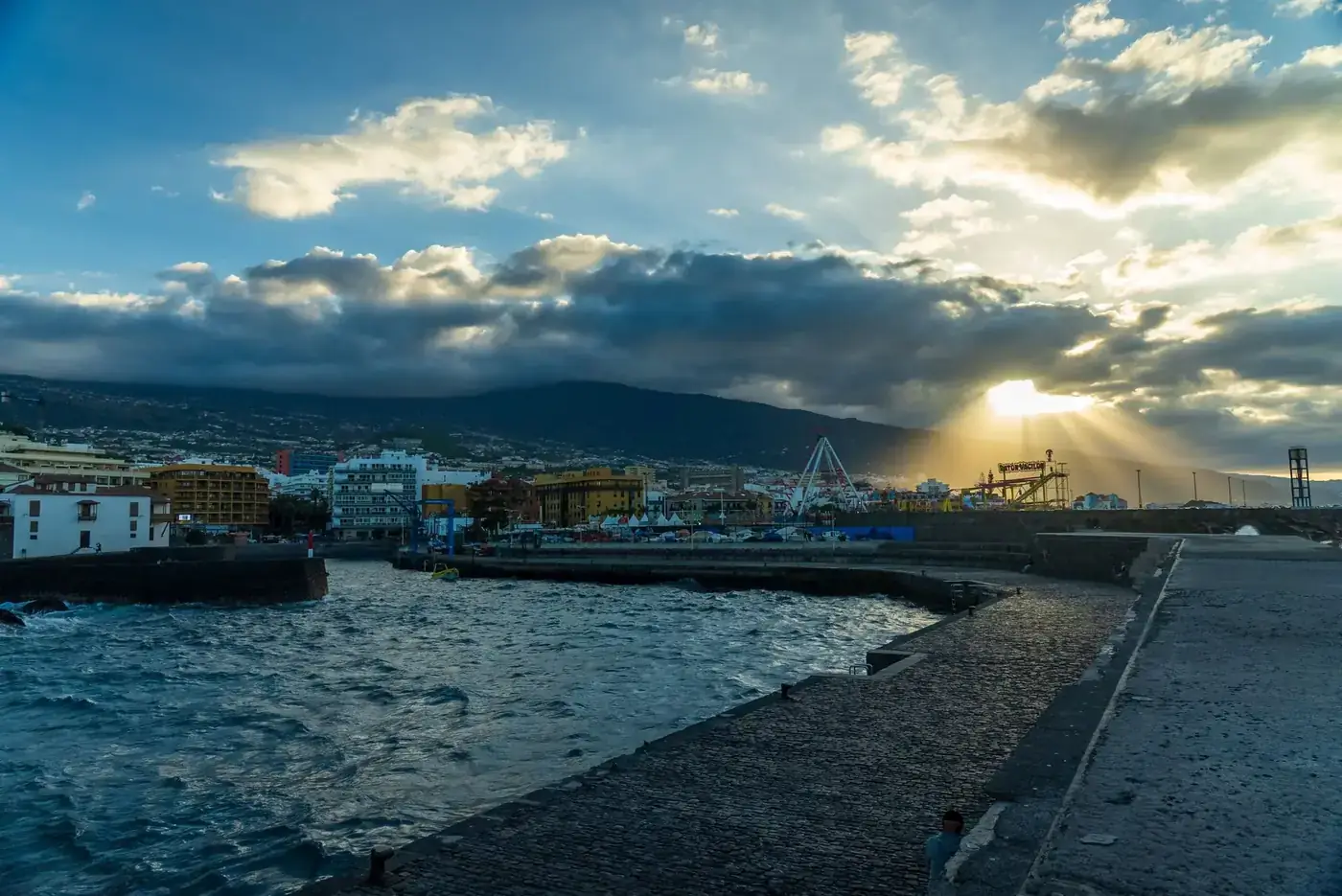 Beautiful sunrise at Puerto de la Cruz harbor, Tenerife with dramatic clouds and urban landscape.
