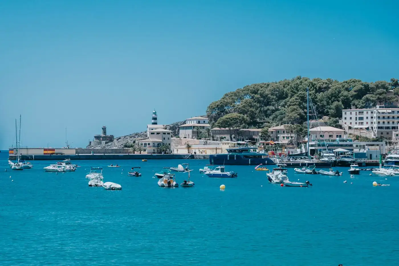 A vibrant harbor scene with boats and coastal town of Port de Sóller, Mallorca.