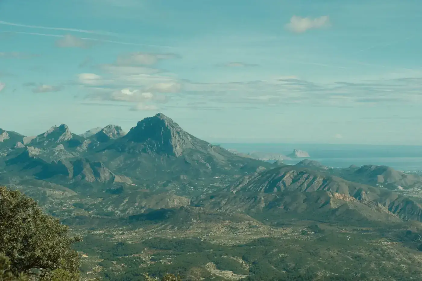 A stunning aerial view of the Puig Campana mountains in Alicante, Spain, showcasing rugged peaks and vast landscapes.
