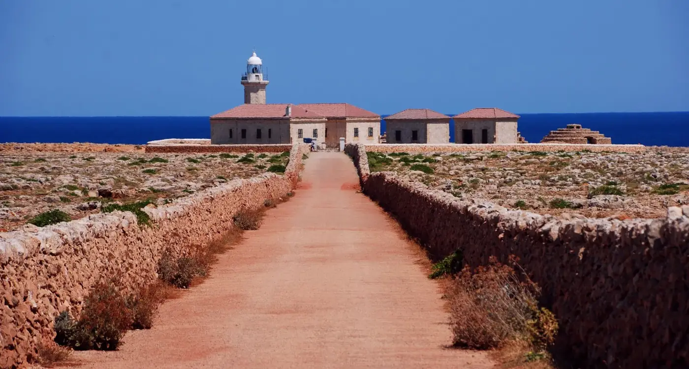 Punta Nati Lighthouse with clear skies and ocean views in Menorca, Spain.