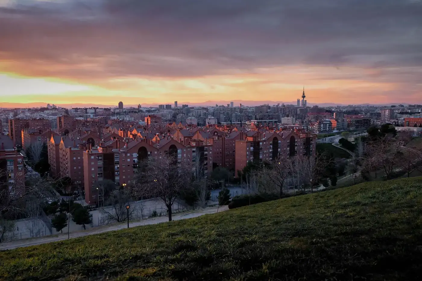 Captivating view of Madrid's skyline at sunset from a park, showcasing urban architecture.