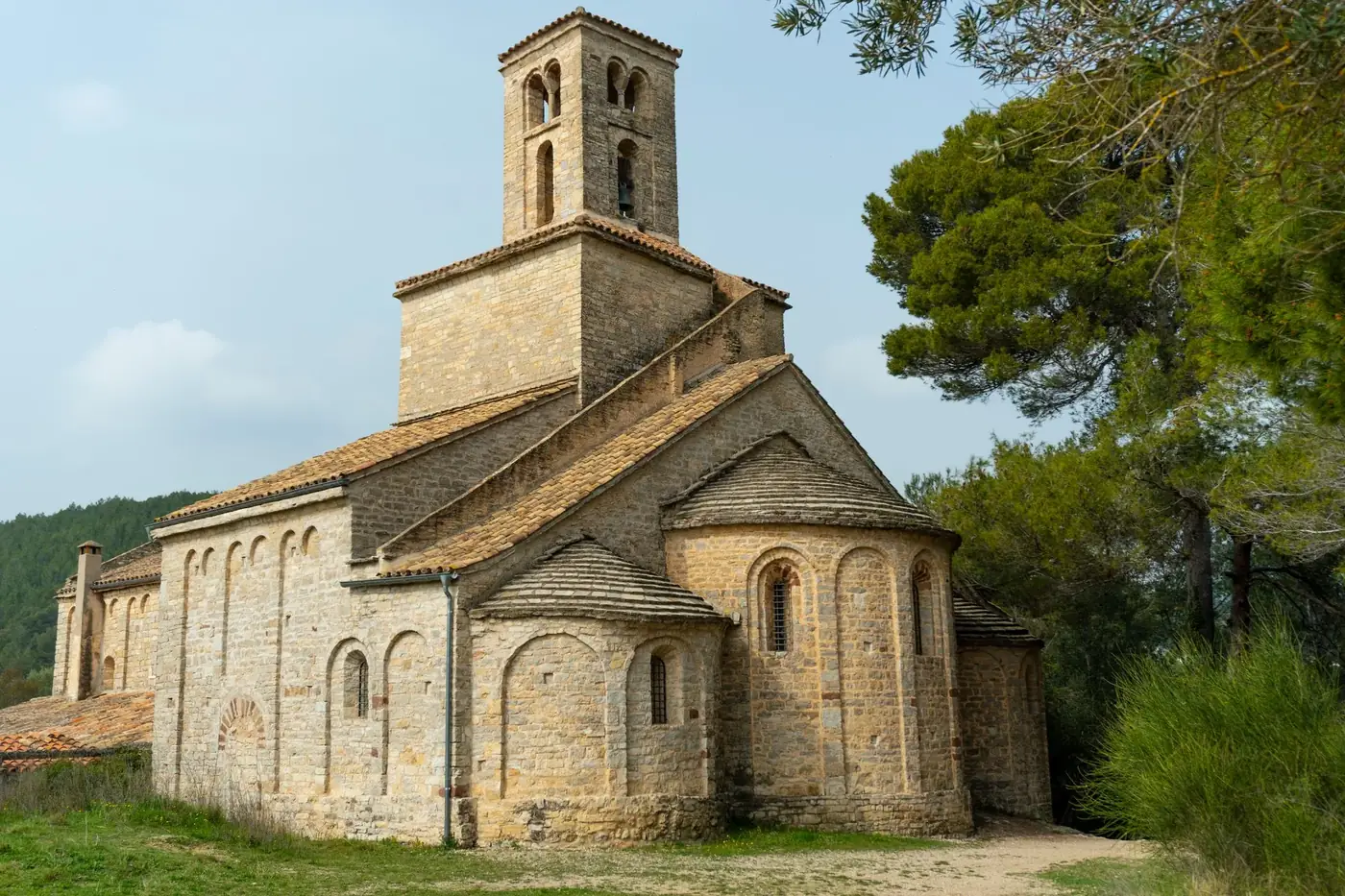 Beautiful stone church surrounded by trees in Corbera de Llobregat, showcasing Romanesque architecture.