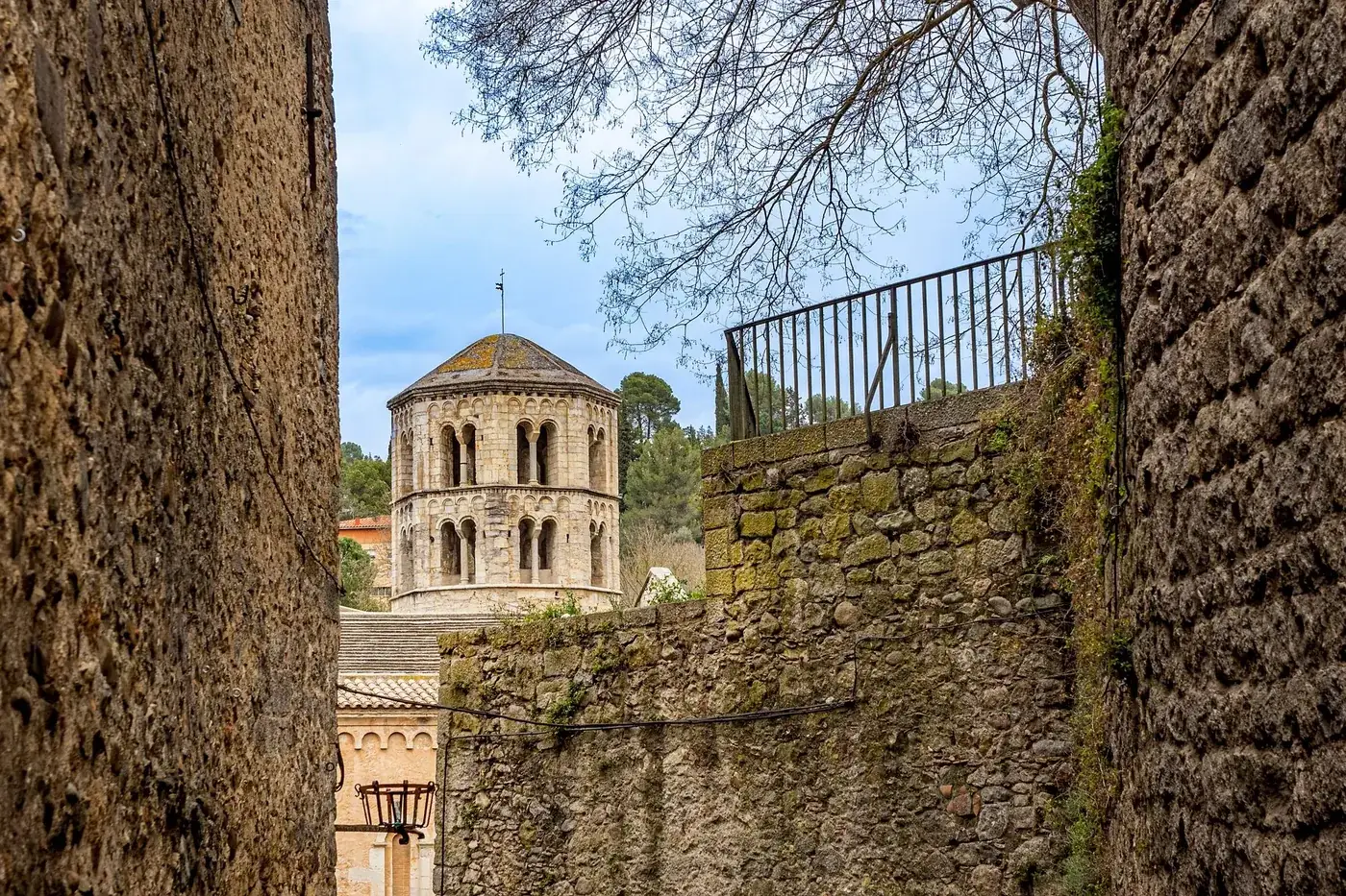 A glimpse of the historic Monastery of Sant Pere de Galligants in Girona through ancient city walls.