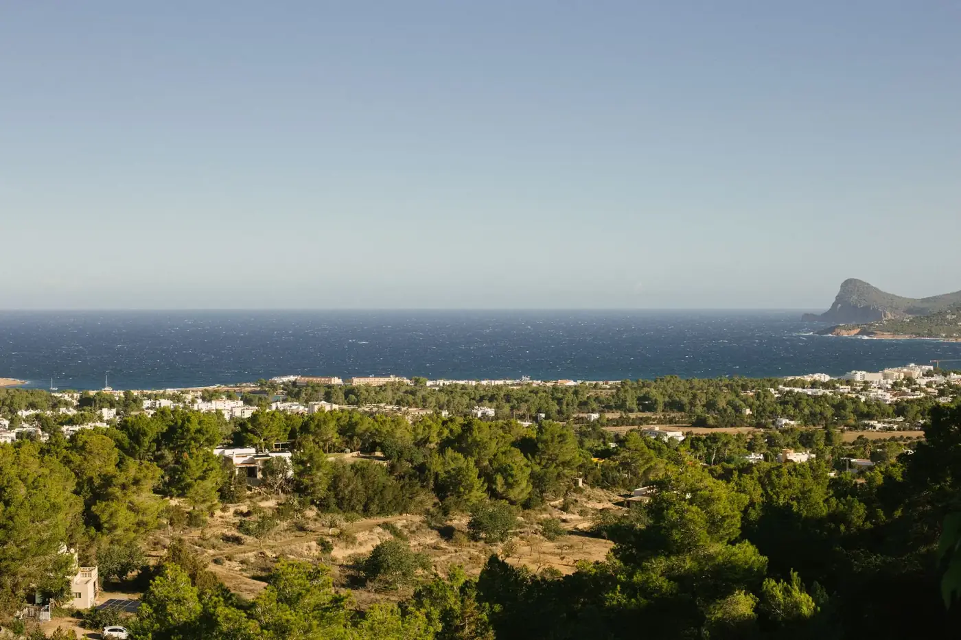 A breathtaking view of Ibiza's coastline with lush greenery and the Mediterranean Sea.