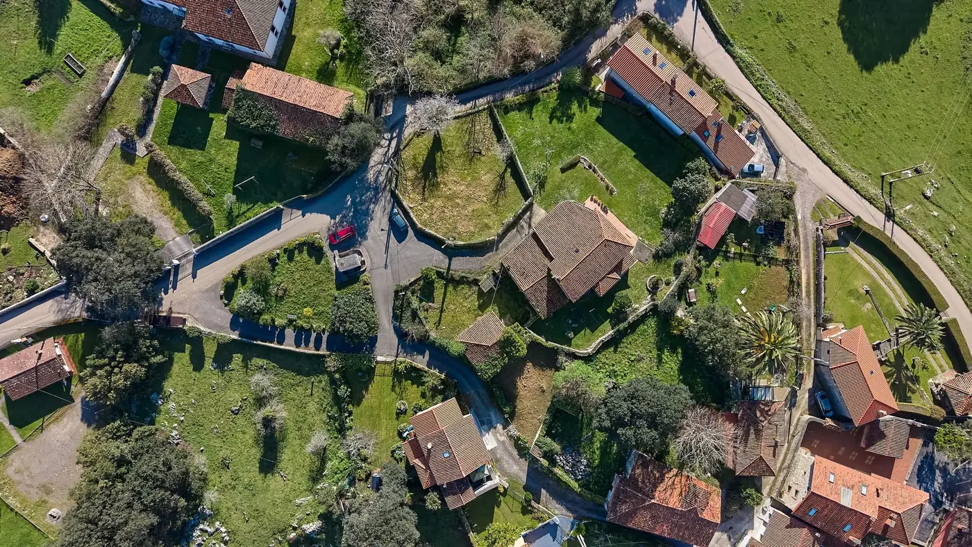 Drone view of picturesque rural village in Cantabria, Spain, showcasing traditional architecture and lush greenery.