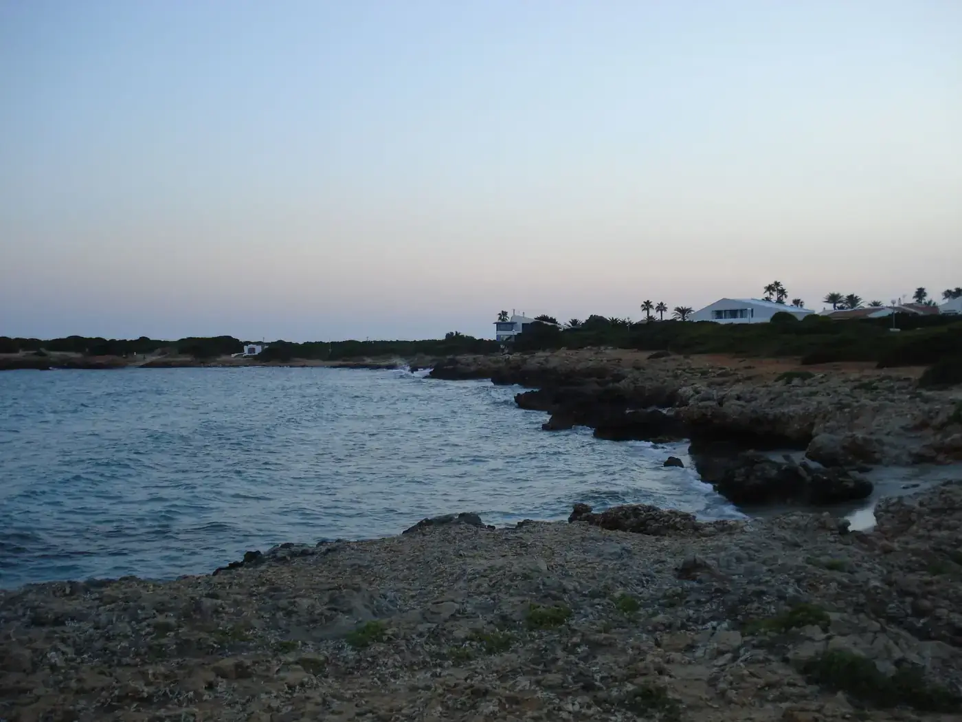 Tranquil dusk scene along the rocky coastline and ocean in Ciutadella, Menorca.