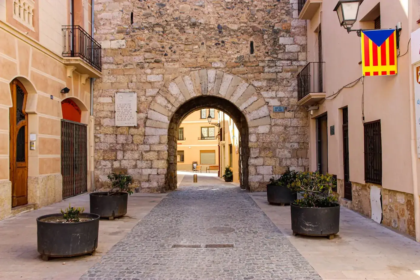 Charming cobblestone street with historic stone archway in Montblanc, Spain.