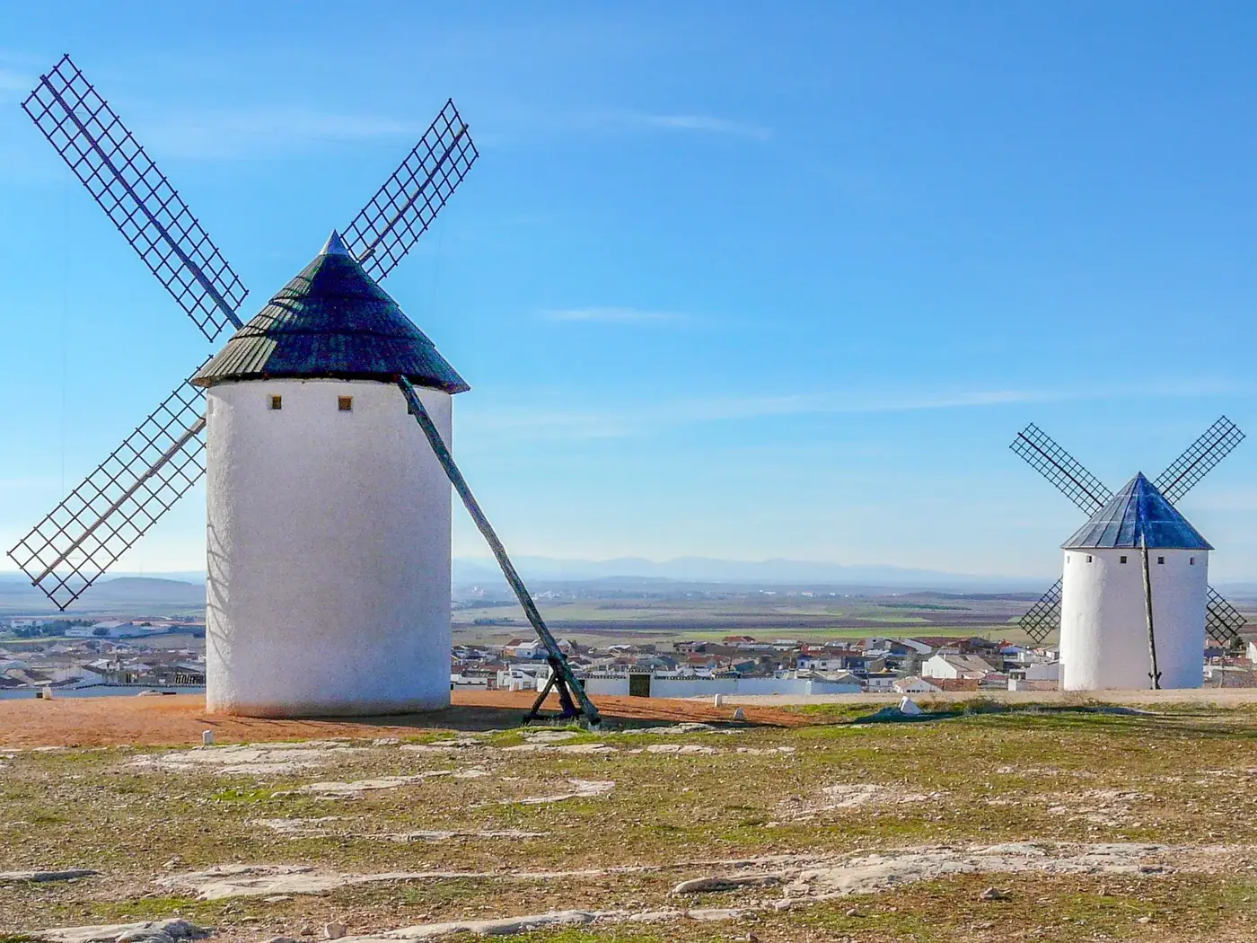 Iconic white windmills in Campo de Criptana, Spain, set against a clear sky.