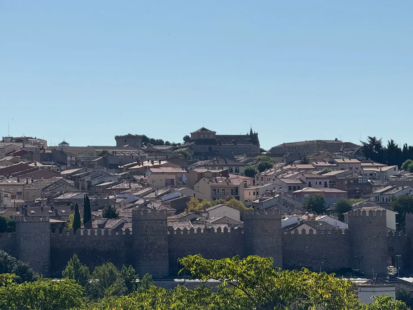 Panoramic view of Ávila's medieval walls under a clear blue sky.