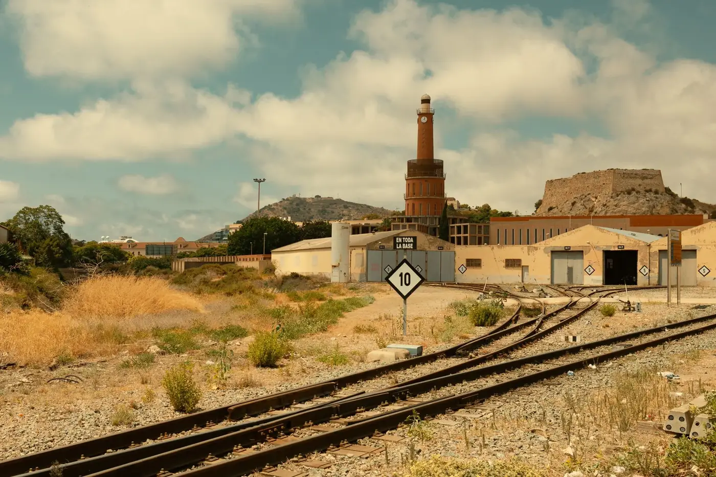 Deserted railway yard with old industrial building and mountain view.