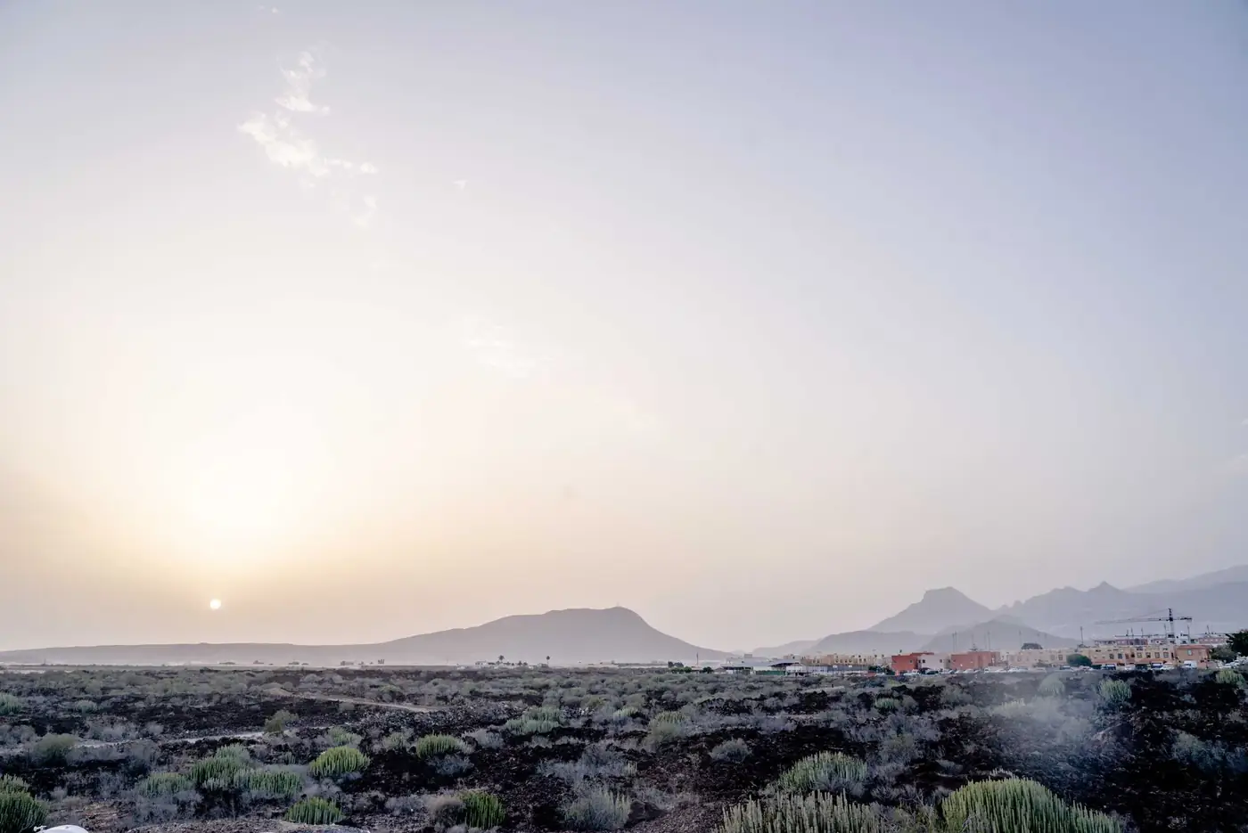 Majestic sunrise over Tenerife's volcanic terrain with distant mountains under a clear sky.