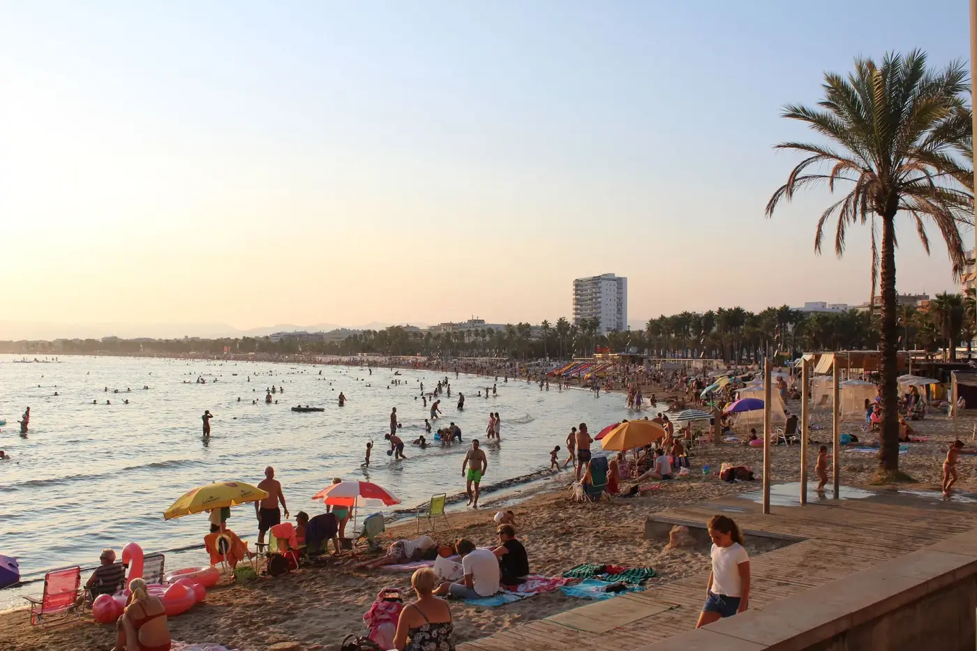 Crowded beach in Spain with people enjoying a sunny day at the shore.