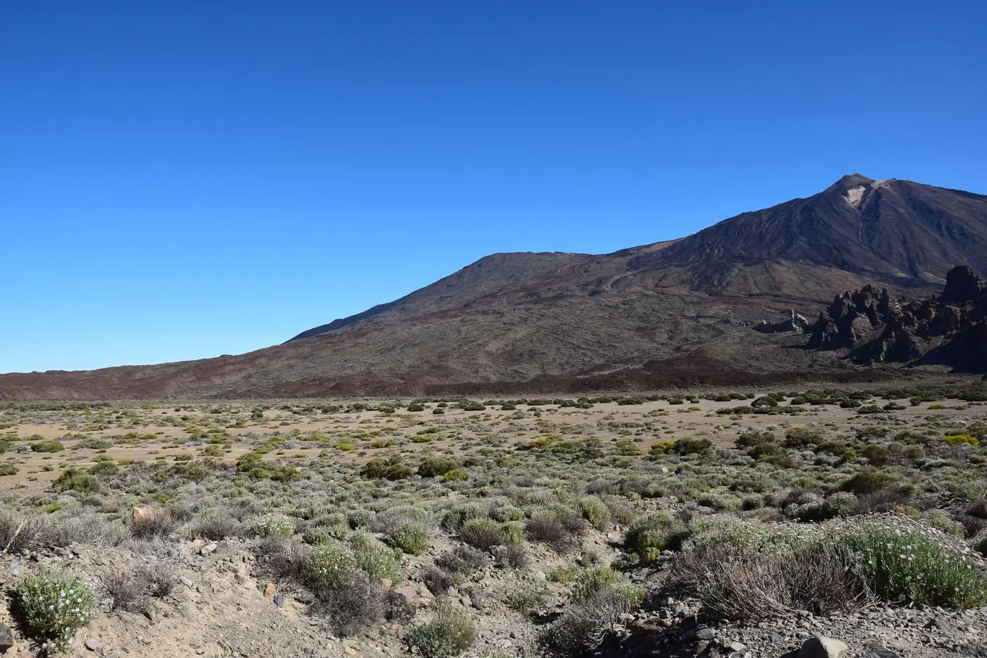 Breathtaking landscape of Mount Teide and arid terrain in Tenerife under clear blue sky.