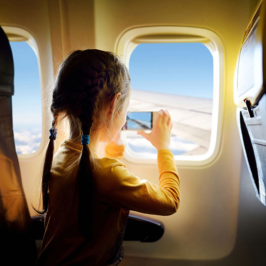 Meisje dat een foto maakt uit het raam van een vliegtuig