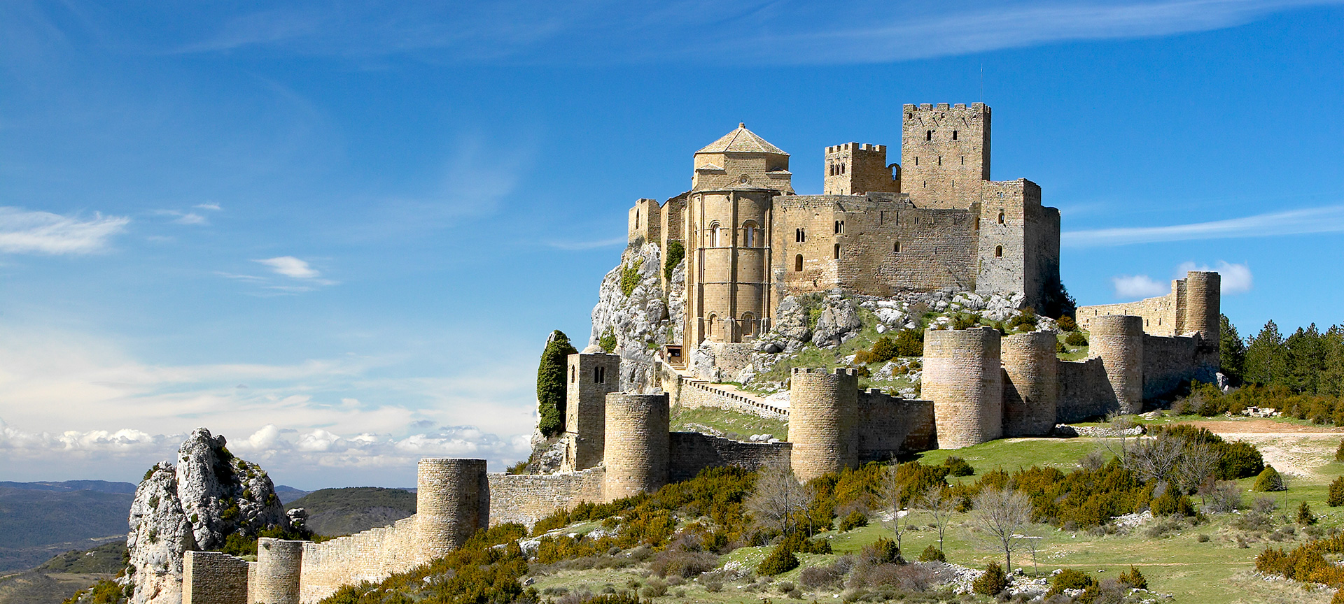 Middeleeuws kasteel op berg tegen blauwe lucht.