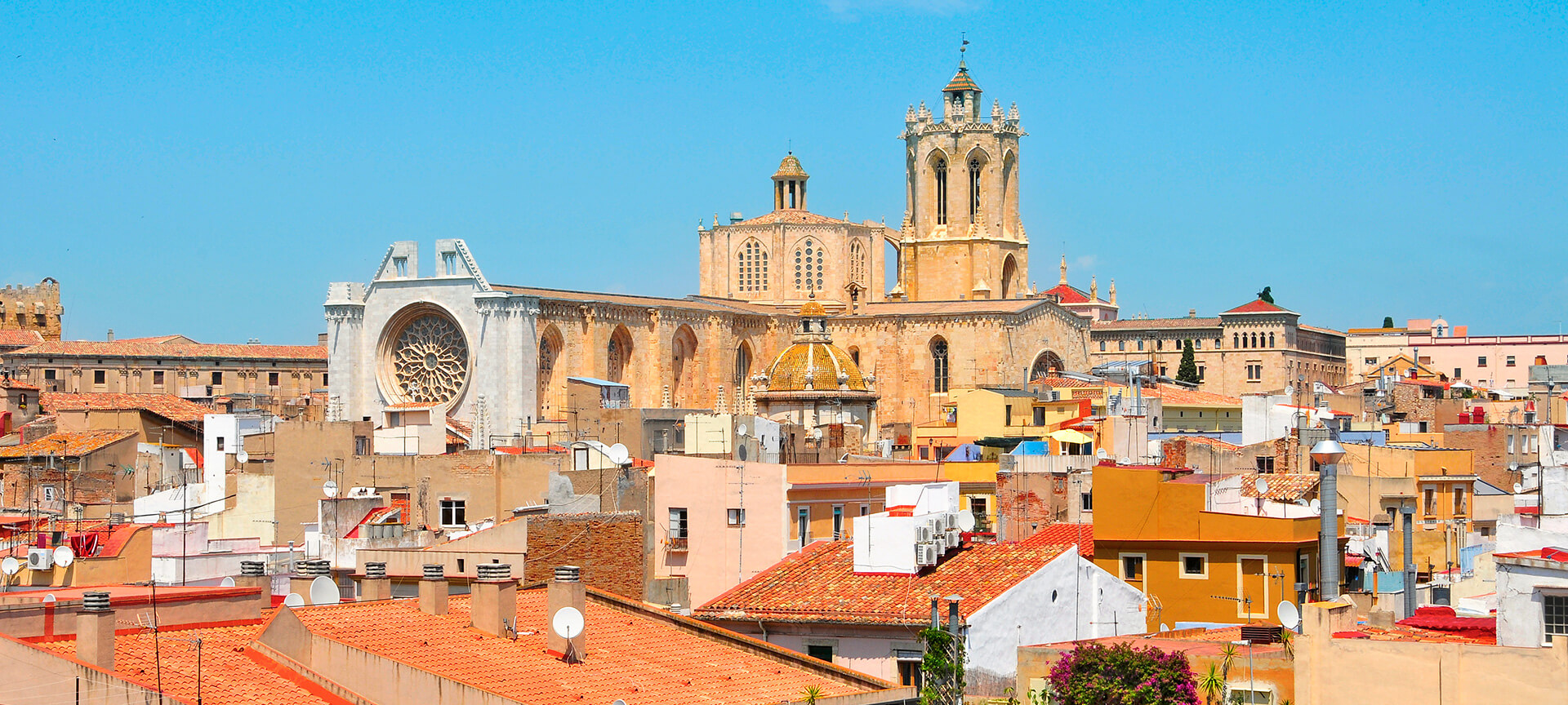 Kleurrijke stad met historische kathedraal onder blauwe hemel.
