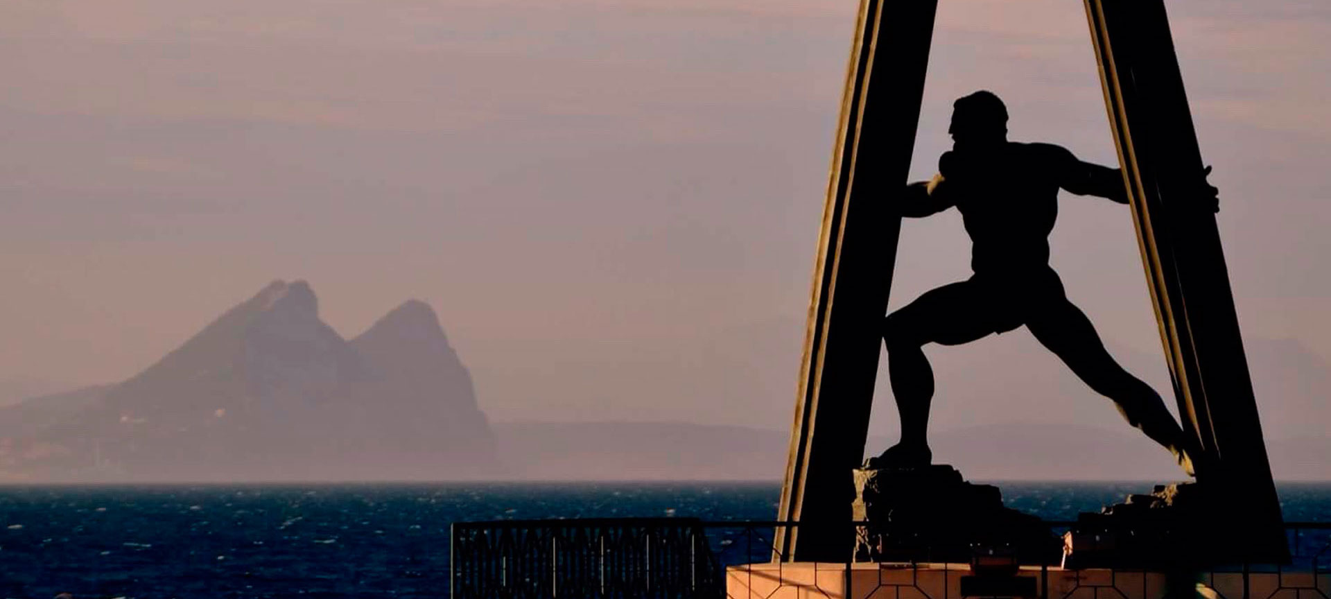 Silhouet van standbeeld met zee en bergen.