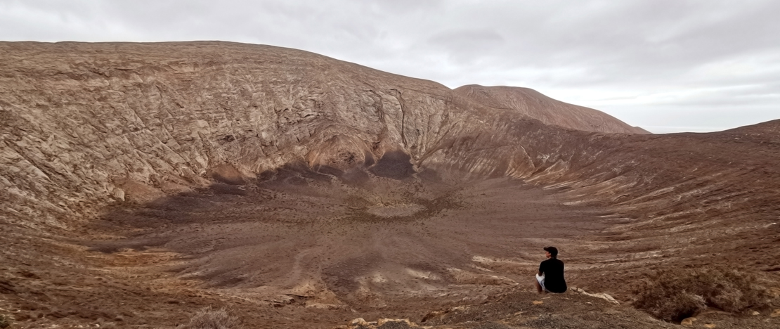 Toerist die naar de Caldera Blanca-vulkaan in Lanzarote, Canarische Eilanden kijkt