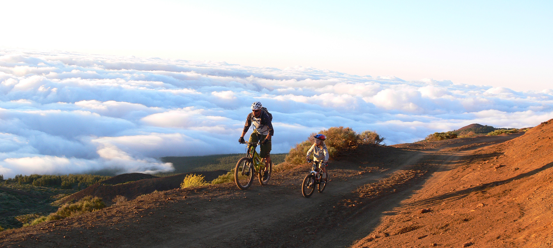 Mountainbikers boven wolken bij zonsondergang.