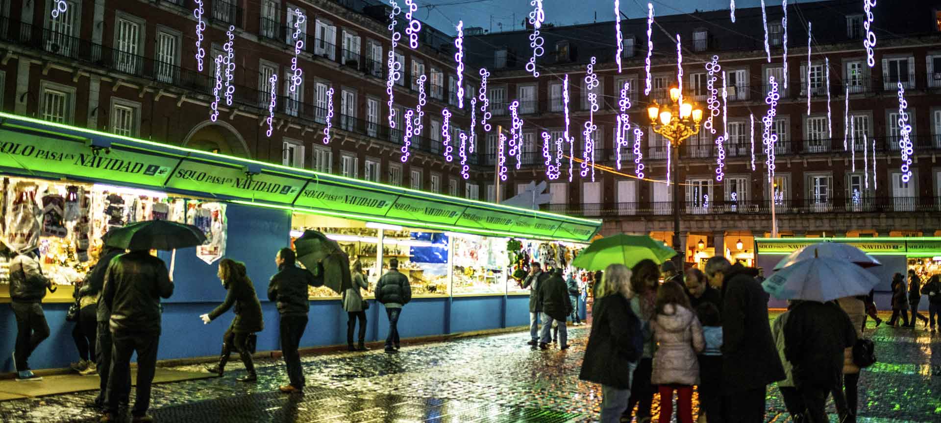 Kerstmarkt 's nachts met regen en feestverlichting.