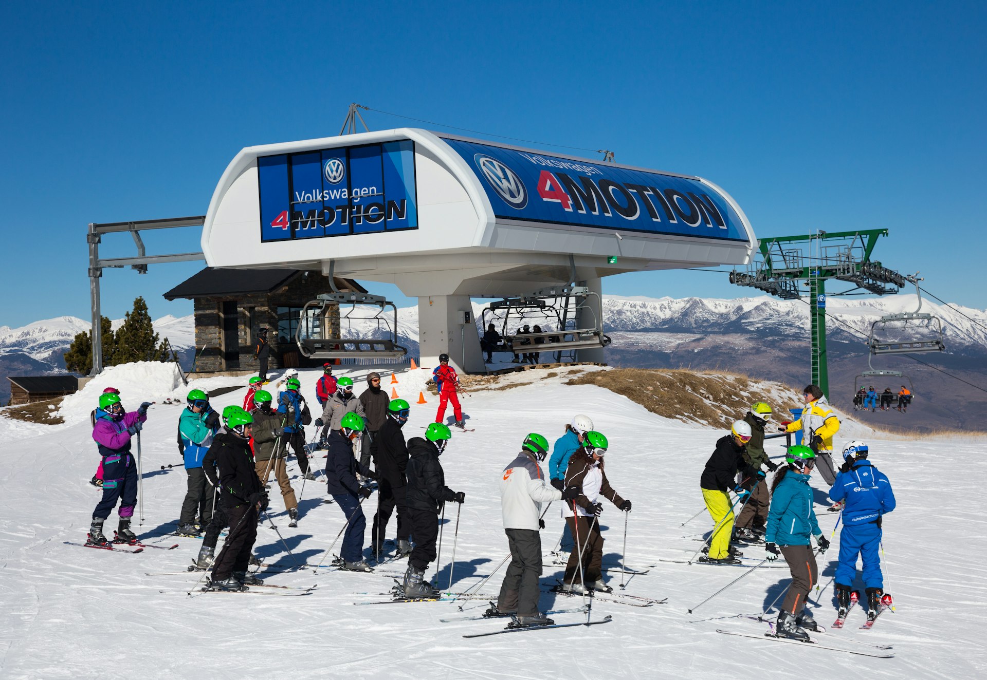 Skiërs op een besneeuwde bergtop met een stoeltjeslift op de achtergrond