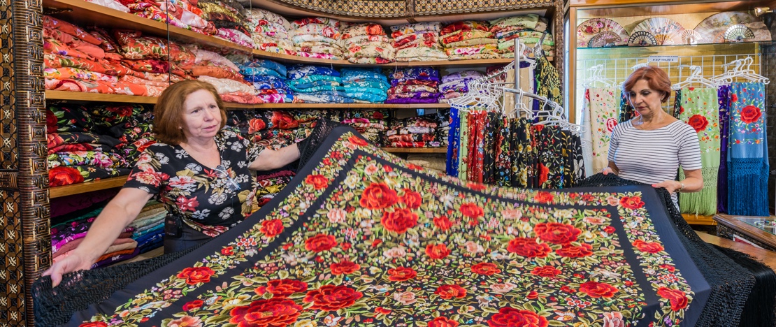 Een vrouw koopt een Manila-sjaal in een winkel in Sevilla